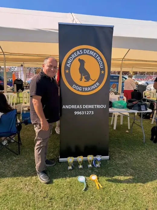 Andreas Demetriou, professional dog trainer in Cyprus, at his dog trainer stand with trophies at a Cyprus dog show